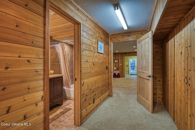 hall featuring light carpet and wood walls