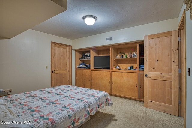 bedroom with light carpet, a textured ceiling, and visible vents