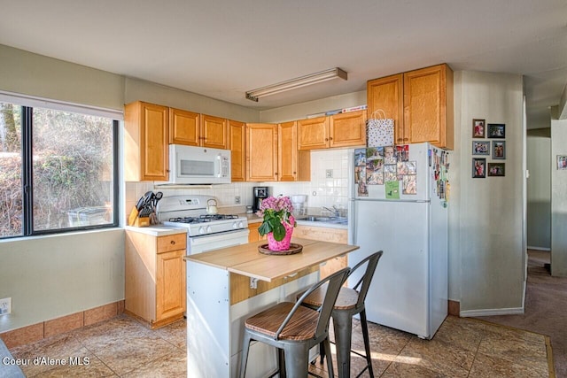 kitchen with tasteful backsplash, white appliances, a sink, and baseboards