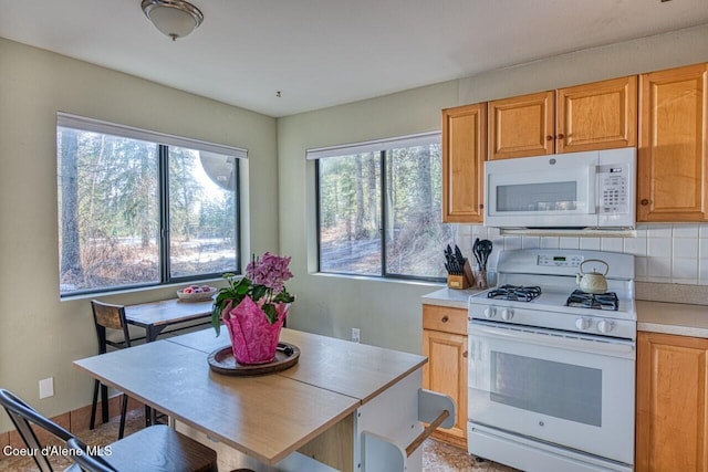 kitchen featuring tasteful backsplash, white appliances, light countertops, and plenty of natural light