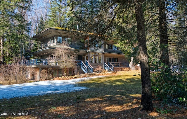 rear view of property featuring driveway, stairway, and a yard