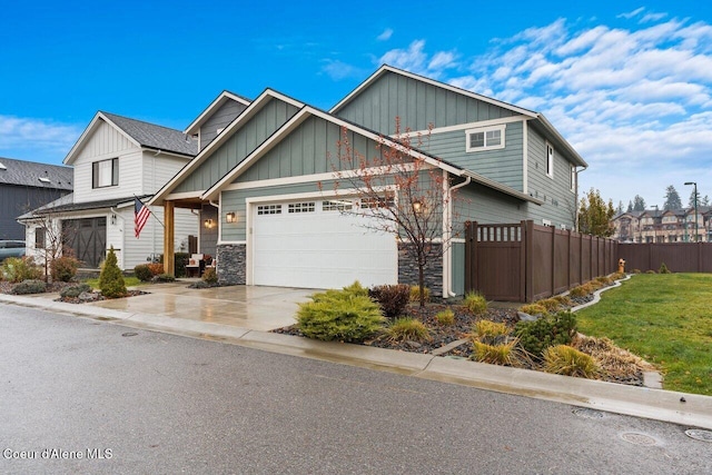 craftsman-style home with driveway, board and batten siding, stone siding, and fence