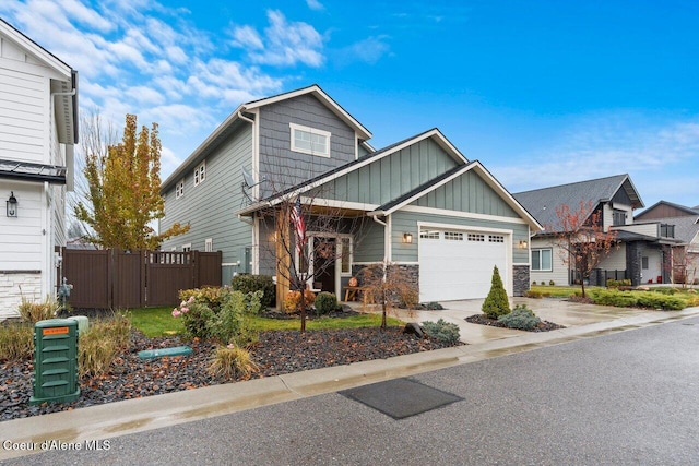 view of front of property featuring an attached garage, board and batten siding, fence, stone siding, and driveway