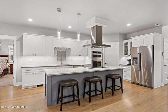 kitchen featuring appliances with stainless steel finishes, light wood-type flooring, white cabinetry, and island range hood