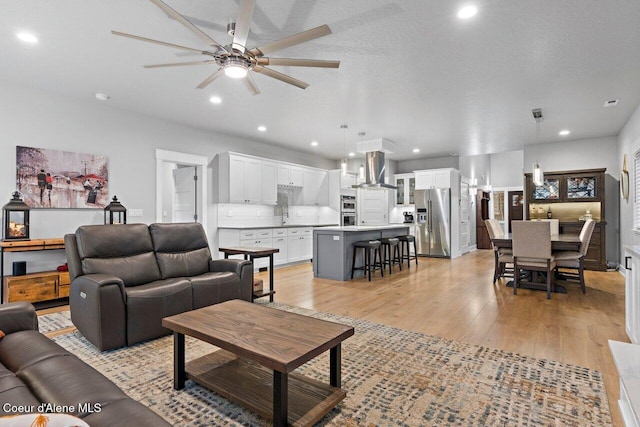 living room with light wood-style floors, recessed lighting, ceiling fan, and a textured ceiling