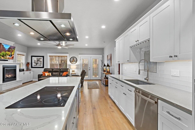 kitchen featuring dishwasher, a glass covered fireplace, open floor plan, black electric stovetop, and a sink