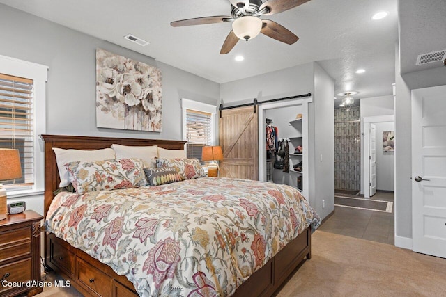 carpeted bedroom featuring a closet, visible vents, a spacious closet, and a barn door