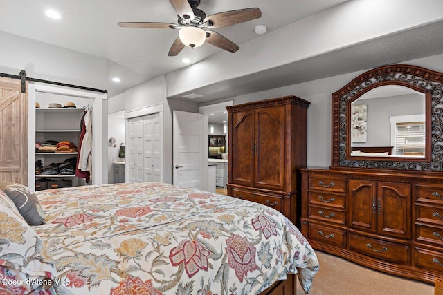 bedroom featuring a barn door, a ceiling fan, ensuite bath, carpet, and recessed lighting