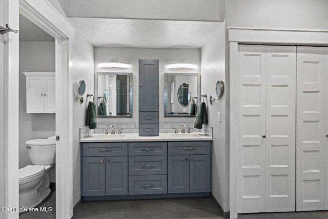 full bath featuring a textured ceiling, a closet, a sink, and toilet