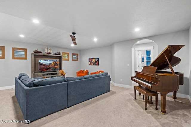 living area with arched walkways, light colored carpet, baseboards, and recessed lighting