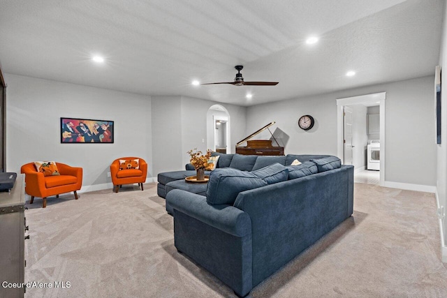 living room featuring recessed lighting, arched walkways, baseboards, and light colored carpet