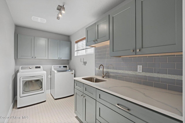 laundry room with a sink, baseboards, cabinet space, light floors, and washer and clothes dryer