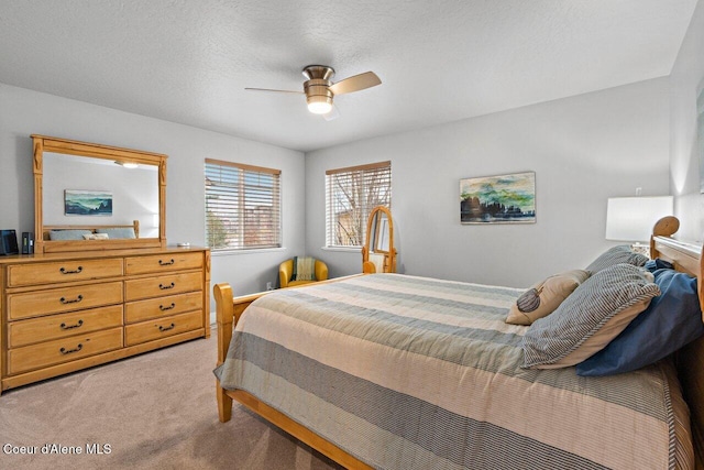 bedroom with light carpet, ceiling fan, and a textured ceiling