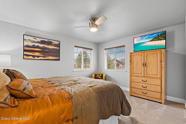 bedroom featuring light carpet, a textured ceiling, a ceiling fan, and baseboards