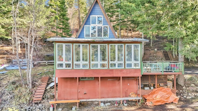 rear view of property with a sunroom, metal roof, a wooden deck, and stairs