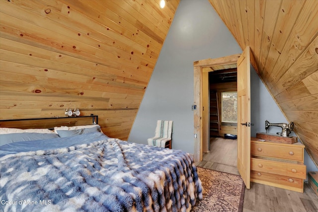 bedroom featuring lofted ceiling, wood walls, wooden ceiling, and wood finished floors