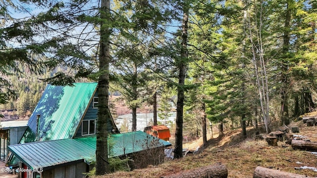 view of side of property with a forest view and metal roof