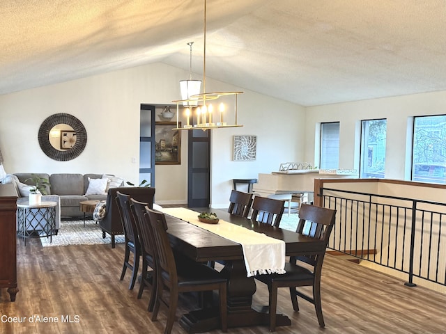 dining room with a chandelier, lofted ceiling, a textured ceiling, and wood finished floors