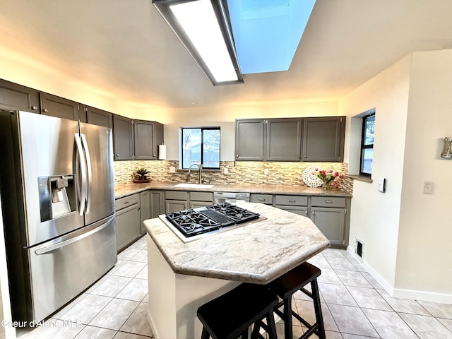 kitchen featuring appliances with stainless steel finishes, a sink, decorative backsplash, and light tile patterned floors