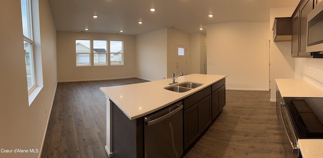 kitchen featuring stainless steel appliances, light countertops, a sink, and dark wood-style floors