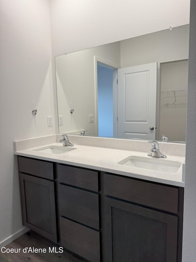 full bathroom featuring double vanity, baseboards, and a sink