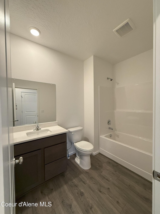 bathroom featuring visible vents, shower / bathing tub combination, toilet, vanity, and wood finished floors