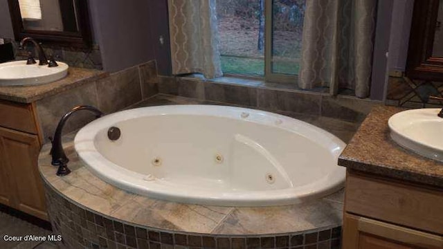 bathroom with two vanities, a sink, and a tub with jets