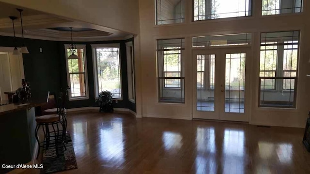 foyer entrance with a tray ceiling, french doors, ornamental molding, wood finished floors, and baseboards