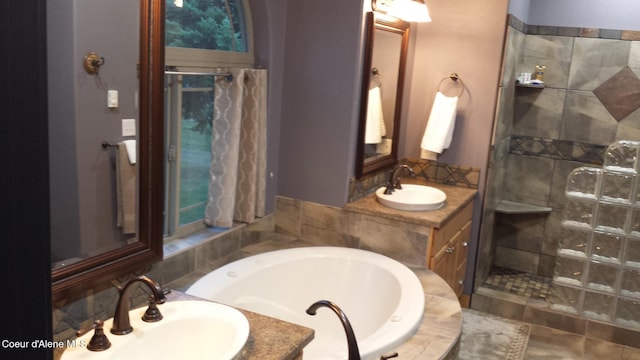 bathroom with a tile shower, a bath, and vanity