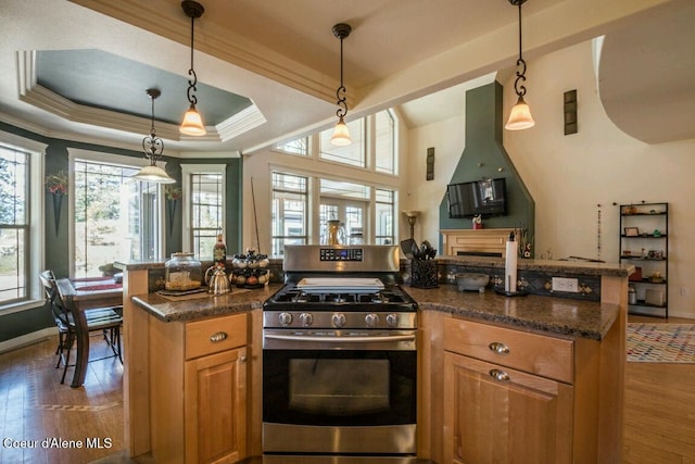 kitchen with a tray ceiling, crown molding, hanging light fixtures, wood finished floors, and gas range