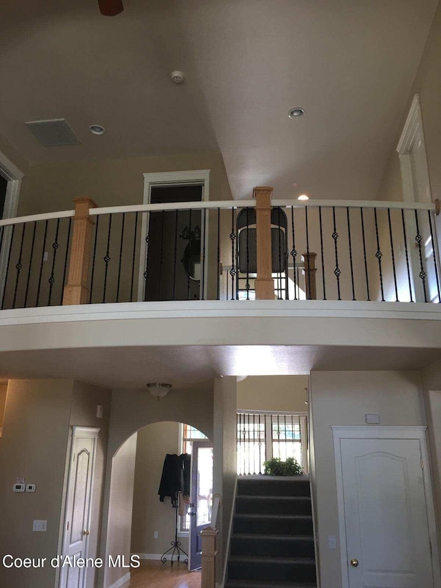 stairway featuring arched walkways, a high ceiling, and recessed lighting