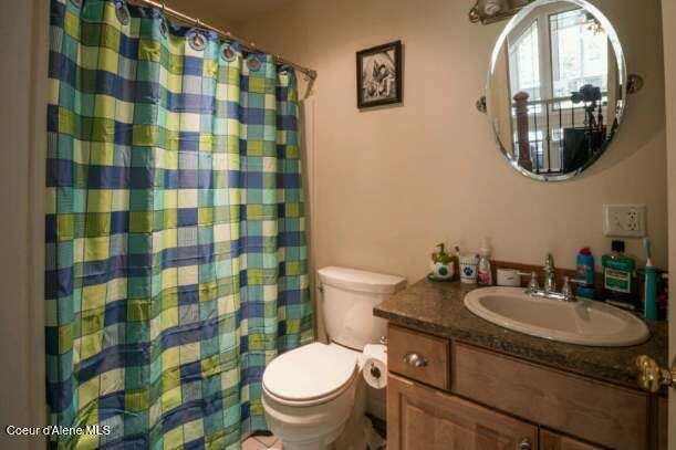 full bath featuring a shower with shower curtain, vanity, and toilet