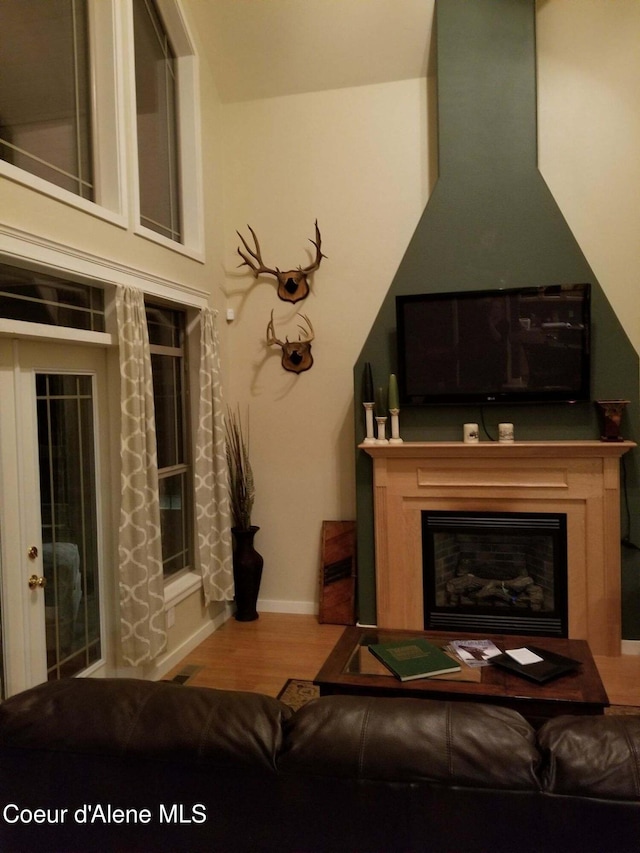 living room featuring a glass covered fireplace, baseboards, and wood finished floors