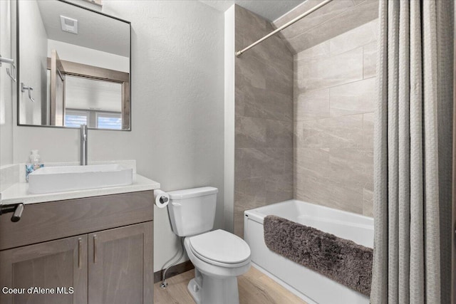 bathroom featuring visible vents, shower / bathtub combination with curtain, toilet, vanity, and wood finished floors