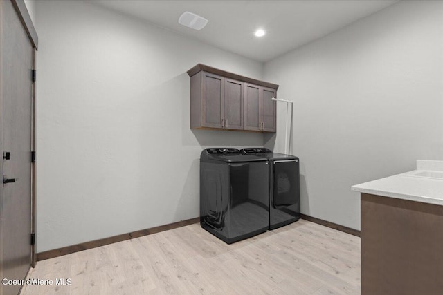 clothes washing area featuring cabinet space, baseboards, separate washer and dryer, and light wood-style floors