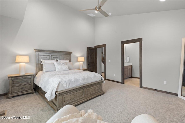 bedroom featuring ceiling fan, high vaulted ceiling, connected bathroom, light colored carpet, and baseboards