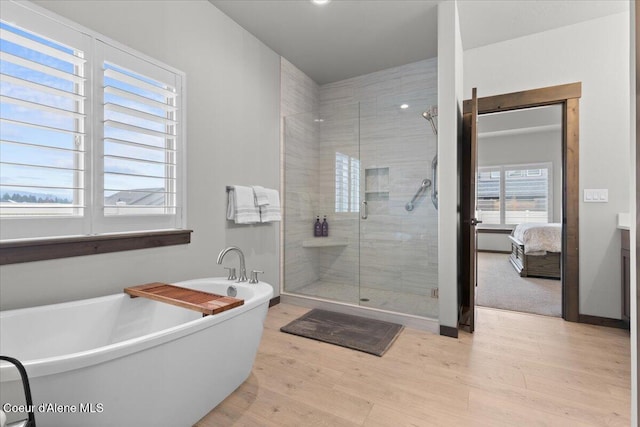 full bath with wood finished floors, baseboards, a soaking tub, a shower stall, and ensuite bath