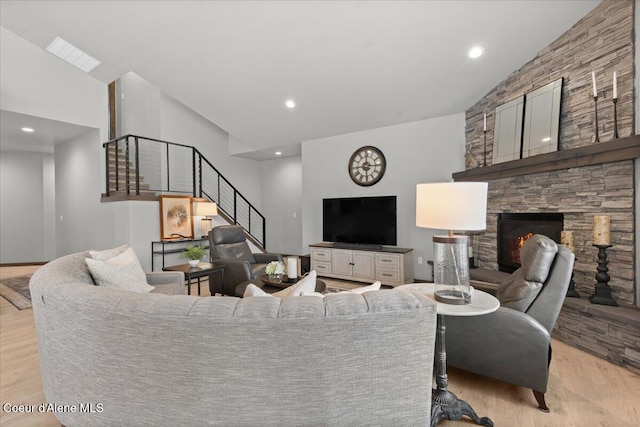 living room featuring light wood-type flooring, a fireplace, recessed lighting, and stairs