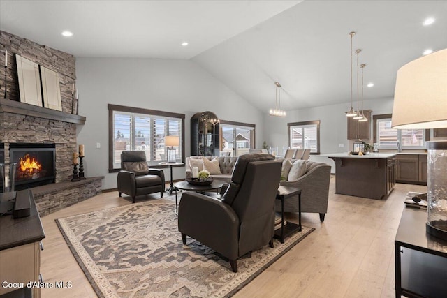 living area featuring plenty of natural light, a fireplace, high vaulted ceiling, and light wood-style flooring