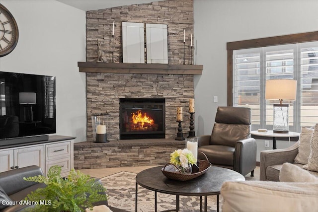 living room featuring vaulted ceiling and a stone fireplace