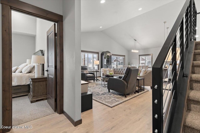 living area with a chandelier, high vaulted ceiling, recessed lighting, light wood-style floors, and stairs