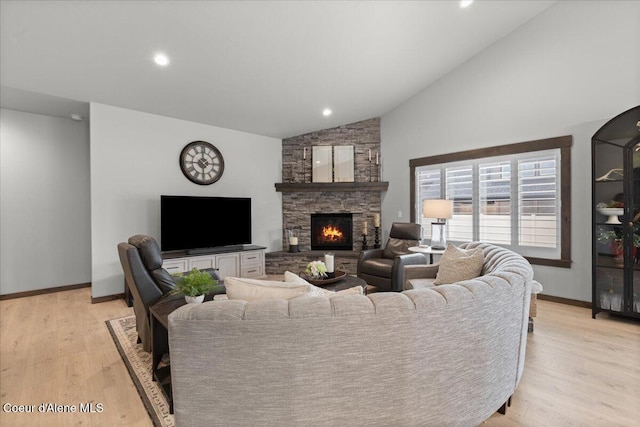 living area with light wood finished floors, baseboards, high vaulted ceiling, and a stone fireplace