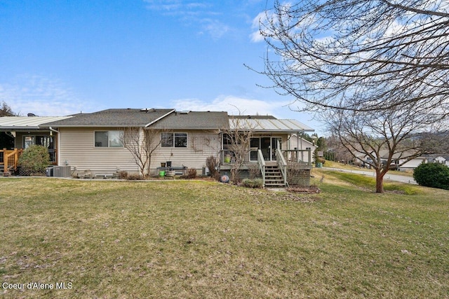 back of property with a lawn, stairway, and central air condition unit