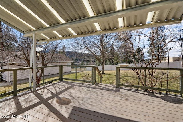 wooden terrace featuring a yard and fence