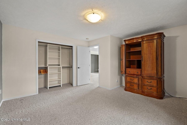 unfurnished bedroom with a textured ceiling, a closet, baseboards, and light colored carpet