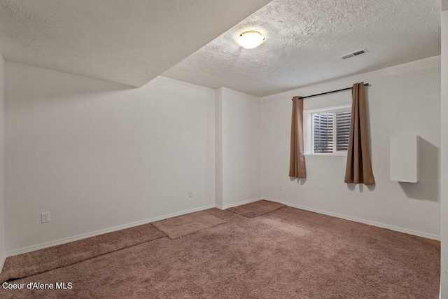 empty room featuring a textured ceiling, carpet, visible vents, and baseboards