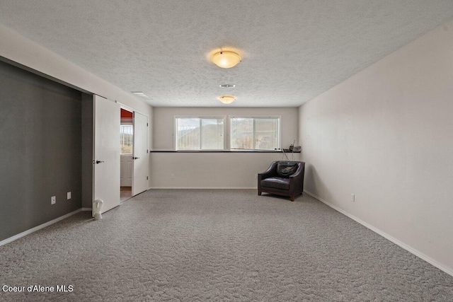 unfurnished room with plenty of natural light, carpet, baseboards, and a textured ceiling