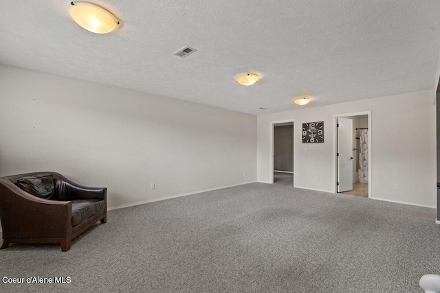 interior space with a textured ceiling, carpet, visible vents, and baseboards