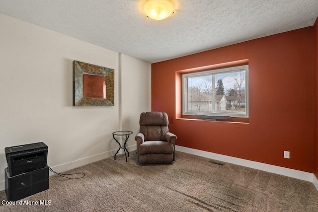 living area with visible vents, carpet flooring, a textured ceiling, and baseboards