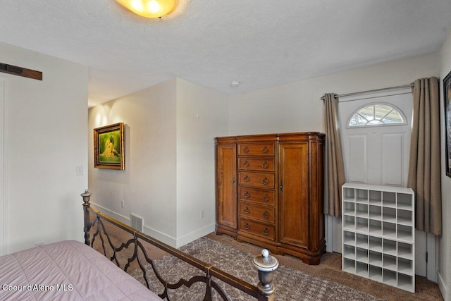 carpeted bedroom featuring a textured ceiling, a barn door, visible vents, and baseboards